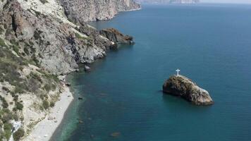 Aerial view of rocky coast and blue sea. Action. Flying above steep slopes of a mountain range, cliffs above calm water surface, summer nature landscape. video
