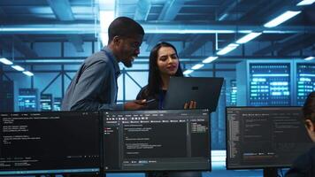 Technician and team leader in server farm looking for equipment misconfigurations affecting performance. Multiethnic coworkers checking data center infrastructure bottlenecks leading to glitches video