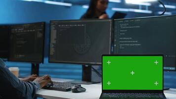 Expert in server hub workspace using isolated screen PC monitor to repair devices storing datasets. Technician using chroma key computer to do servicing on rigs doing computational operations video