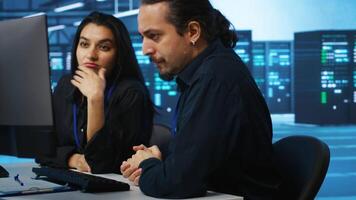 IT technicians in server farm brainstorming ways to repair equipment storing datasets. Colleagues at work in data center discussing how to mend rigs doing computational operations video