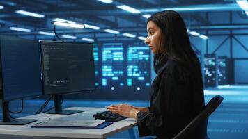 Technician working in high tech server room, analyzing data on multiple monitors, ensuring seamless data flow. Woman examining racks in data center, ensuring system integrity and security video