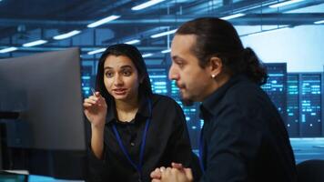 Programmers talking in high tech server hub, using PCs to analyze data. Colleagues examining infrastructure in data center, ensuring system integrity and security, doing brainstorming video