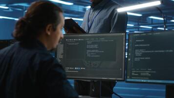 Manager overseeing team and doing system analysis of server farm supercomputers using tablet. Man supervising employees in data center housing storage infrastructure supporting critical IT workloads video