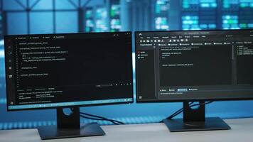 Computers in empty data center facility managing rackmounts energy consumption. Close up of script on PC monitors used for automation and monitoring processes in server room, camera B video