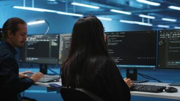 Diverse IT engineers in server room brainstorming ways to fix equipment storing datasets. Multiethnic coworkers discussing how to mend data center racks doing complex computational operations video