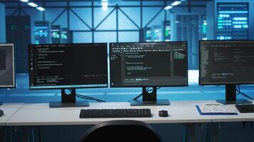Computers in empty high tech data center establishment monitoring hardware energy consumption. PC monitors on desk used for checking potential system failures in server room video