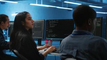 Multiethnic team of engineers working in high tech server hub, using PCs to analyze data. Multiracial group of employees examining infrastructure in data center, ensuring system integrity and security video
