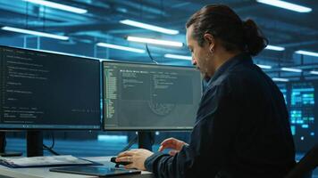 System admin focused on programming in server room housing advanced equipment storing massive datasets. Developer typing code on PC to mend data center racks doing complex computational operations video