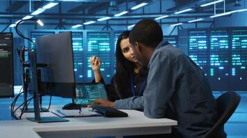 Multiethnic coworkers doing system analysis of server farm supercomputers using tablet. Diverse team of engineers looking at parameters in data center housing storage infrastructure video