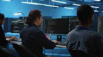 Multiracial coworkers in data center coding and checking parameters on computer. Multiethnic team working together, doing programming in high tech workspace, overseeing server clusters video