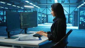 System administrator at PC desk working in computer network security data center, ensuring optimal performance. Employee monitoring energy consumption across operational server rigs components video