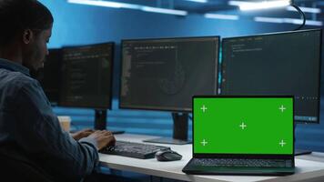 Isolated screen laptop next to programmer coding in server farm, ensuring valuable data remains shielded from threats. Worker safeguarding hardware against unauthorized access with chroma key notebook video
