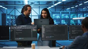 Programmer and supervisor in server room looking for equipment misconfigurations, doing brainstorming. Multiracial colleagues checking data center gear bottlenecks leading to glitches video