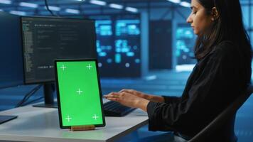 Focus on isolated screen tablet next to admin programming in server room providing computing resources for workloads. Chroma key device on desk used by worker supervising data center supercomputers video