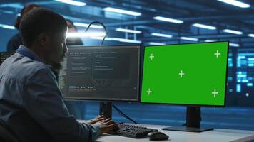IT specialist in server farm using green screen PC ensuring valuable data remains shielded from threats. Man safeguarding hardware against unauthorized access and vulnerabilities using mockup computer video