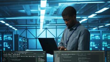 Manager in server hub using laptop to find firewall misconfigurations affecting rackmounts performance. Supervisor checking systems bottlenecks leading to sluggish data transfer rates video