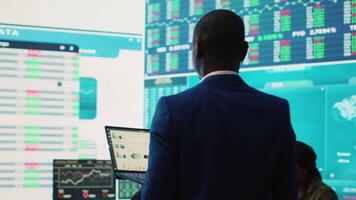 Administrative assistant examining important big data visualizations on a huge display, creating an analysis to review key performance indicators and business efficiency. Camera A. video