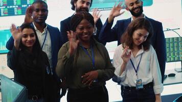 Confident smiling enterprise team uniting their forces to improve workflow and efficiency, achieve organizational goals. Diverse group of analysts work in telecommunications control room. Camera A. video