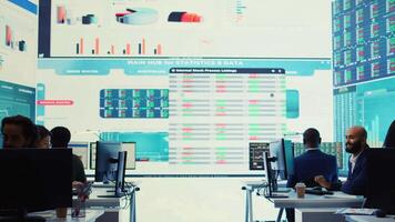 Company employees employing big data used in solving tasks, studying infographics on a huge display. Business analysts reviewing current situation numbers for annual reports. Camera B. video