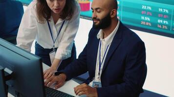 companheiros de equipe examinando Estatisticas e infográficos em computador dentro ao controle sala, juntando forças para reunir discernimento para o negócio desenvolvimento. analistas discutindo legal mudanças. Câmera uma. video