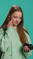 Vertical Young girl suffering from illness upset about needing to take medicine, holding pill bottle. Ill woman preparing to take need dose of vitamin supplements, studio background, camera A video