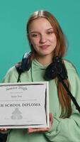 Vertical Overjoyed student celebrating achievement, holding diploma, using microphone to do speech, studio background. Woman using mic to share wisdom with colleagues after finishing school, camera A video