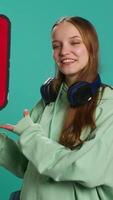 Vertical Smiling woman holding red speech bubble sign of empty copy space for message. Joyous teenager presenting thought bubble cardboard used as promotion concept, isolated over studio background, camera A video