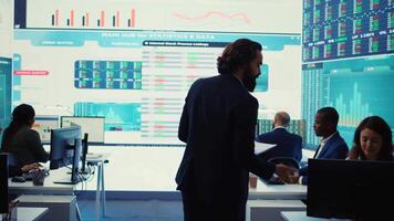Financial manager briefing his team members about new corporation objectives, presenting their budget scheme with expenses. Resource allocation and project planning in control room. Camera B. video