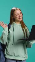 Vertical Smiling woman having friendly conversation with friends during teleconference meeting using laptop, studio background. Girl having fun catching up with mates during online videocall, camera B video