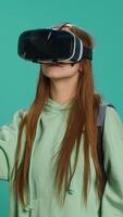 verticaal vrouw vervelend virtueel realiteit koptelefoon, aan het doen vegen gebaren. technologie liefhebber gebruik makend van hoog tech futuristische modern vr apparaatje, geïsoleerd over- studio achtergrond, camera een video