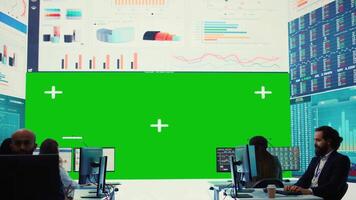 Business partners working in telecommunications control room with a big isolated mockup screen, reviewing key performance indicators within the enterprise activity. Conducting evaluations. Camera A. video