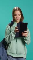 Vertical Woman scrolling on tablet touchscreen, checking social media feed, catching up with friends. Happy person relaxing by browsing internet websites, isolated over studio background, camera B video