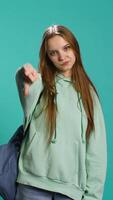 Vertical Frustrated woman showing thumbs down sign gesturing, disapproving and offering negative feedback. Disappointed girl doing dislike hand gesture, studio background, camera B video