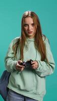 Vertical Young girl spamming controller buttons, disappointed after receiving game over screen. Woman upset after losing videogame, playing with gamepad, studio background, camera B video