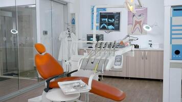 Interior of stomatology orthodontic hospital office with nobody in it ready for dental surgery equipped with modern dentistry tooth instruments. Orthodontist room with teeth xray images on display video