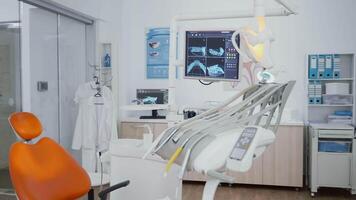 Revealing shot of orthodontist chair with nobody in, dental x ray images on display. Clinic stomatology hospital room, ready for medical treatment, modern dentist office prepared for oral care video