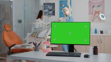 Monitor with green screen on desk in dentist office for dental checkup and oral care. Computer with horizontal chroma key and mockup template for dentition treatment and teethcare video