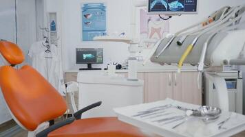 Revealing shot of orthodontist chair with nobody in, tooth x ray images on display. Medical clinic stomatology dentistry room, ready for dental treatment, modern dentist office for oral care video