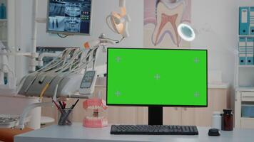 Monitor with green screen on desk in empty dentist office. Nobody in stomatological cabinet with oral care equipment and chroma key for mockup template and isolated background. video