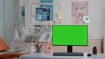 Empty dental cabinet with horizontal green screen on monitor. Nobody in dentist office for dentistry care with isolated background and mockup template on computer. Stomatological tools video