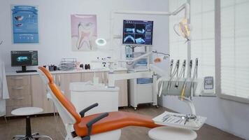 Revealing shot of stomatology chair with nobody in it, teeth diagnosis xray images on display. Medical clinic orthodontic empty room, ready for healdcare treatment, modern dentist office for oral care video