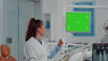 dentista analizando horizontal verde pantalla en monitor y radiografía de dientes para dental cuidado. mujer utilizando croma llave y Bosquejo modelo para oral examen y cuidado de los dientes en gabinete. video