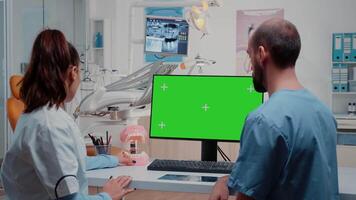 Dentist and nurse looking at green screen on monitor and analyzing teeth layout for stomatological care. Man and woman working with dental equipment for dentistry and teethcare. video