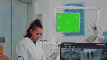 mujer trabajando como dentista con verde pantalla y X rayo escanear para cuidado de los dientes en dental gabinete. oral cuidado especialista analizando croma llave con aislado Bosquejo modelo y dientes radiografía video