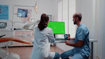 odontología equipo analizando dientes X rayo y verde pantalla en monitor a dentista oficina. especialista y hombre enfermero trabajando con aislado Bosquejo modelo y radiografía para cuidado de los dientes. video