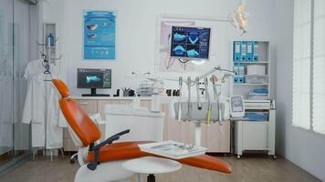 Zoom in shoot of stomatology orthodontist office room with tooth xray images on monitor ready for dental surgery. Orthodontic dentistry workplace equipped with dentist chiar and teeth instruments video