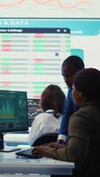 Vertical Financial analyst works on resource allocation plans with his staff, analyzing reports and sales infographics to find revenue. Achieve objectives in a competitive business environment. Camera B. video