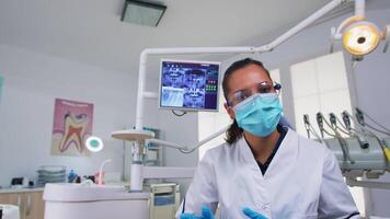 läkare mätning kvinna temperatur innan dental undersökning, patient pov. tandläkare och sjuksköterska arbetssätt i modern ortodontisk kontor, skrivning och granskning person bär skydd mask video