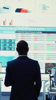 Vertical Administrative assistant examining important big data visualizations on a huge display, creating an analysis to review key performance indicators and business efficiency. Camera B. video