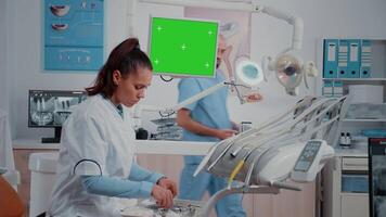 Dentist receiving teeth scan from man while looking at green screen on monitor. Specialist doing oral care examintion with radiography and isolated chroma key in dentistry cabinet video